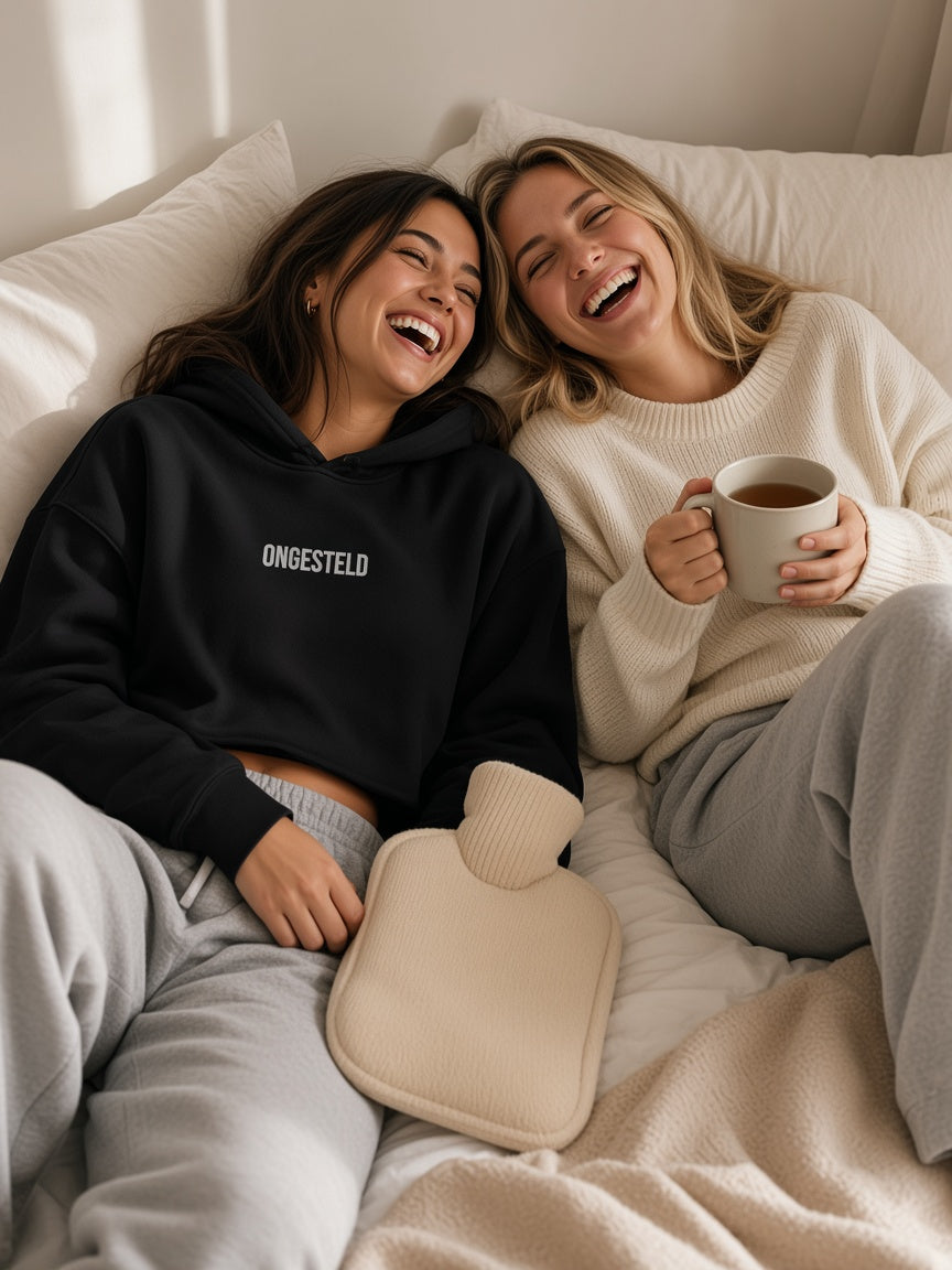 Model draagt de HUMEURIG ONGESTELD Cropped Hoodie in Zwart/Wit met het woord ONGESTELD geborduurd
