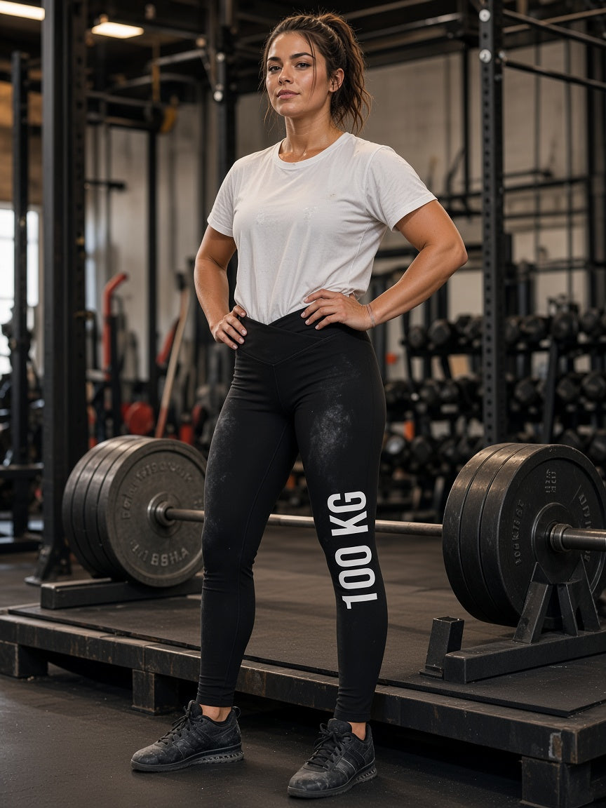 Model draagt de HUMEURIG 100 KG Legging in Zwart met het woord 100 KG bedrukt