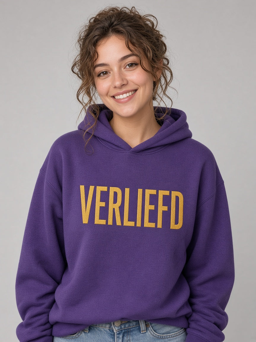 Vrouw draagt de HUMEURIG VERLIEFD Hoodie in paars met goud borduursel (dames)