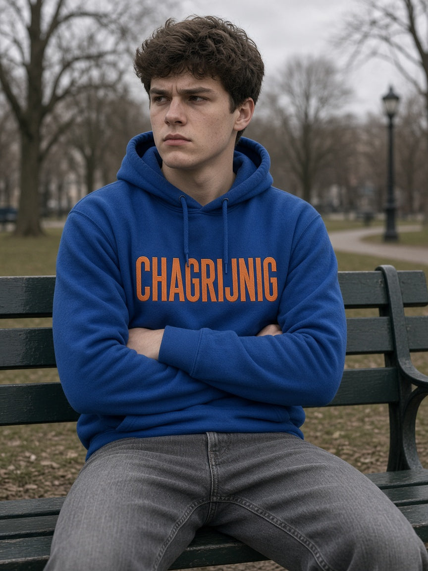 Man draagt de HUMEURIG CHAGRIJNIG Hoodie in royal blauw met oranje borduursel (heren)