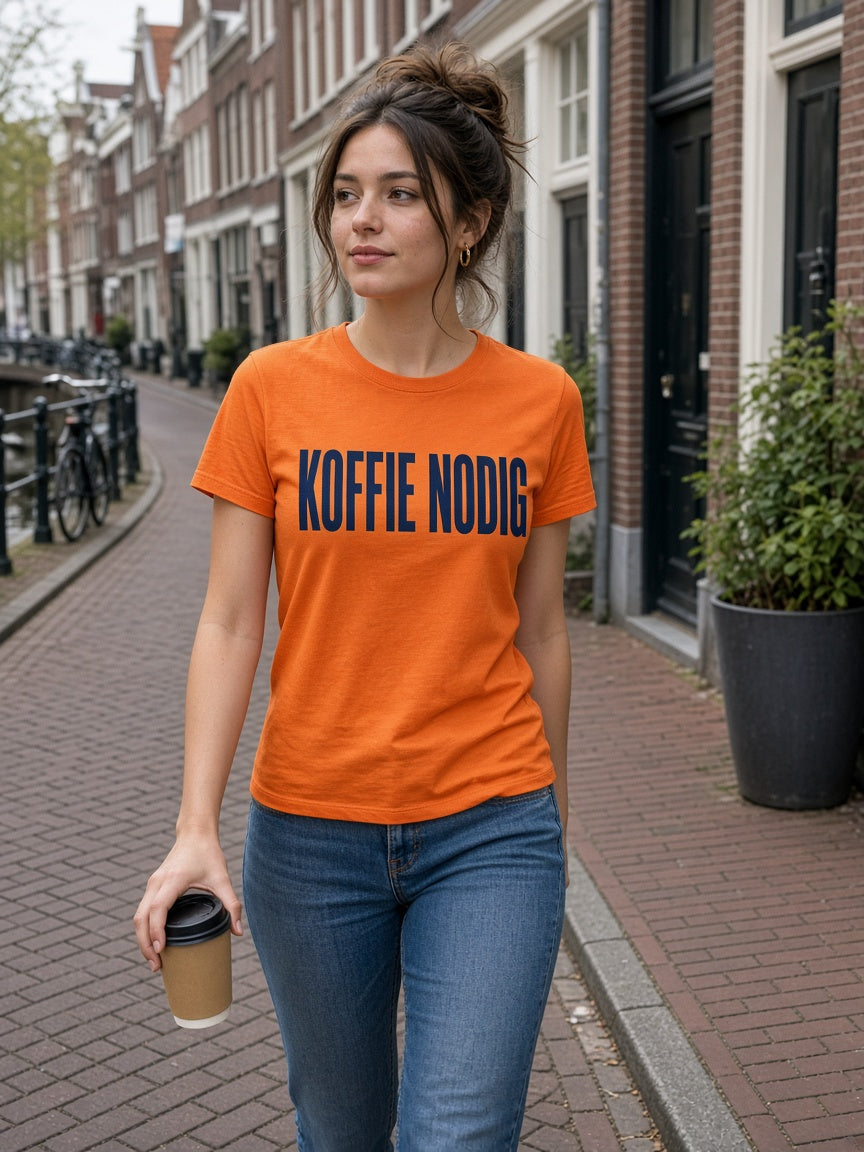 Vrouw draagt de HUMEURIG KOFFIE NODIG Tee in oranje (dames)